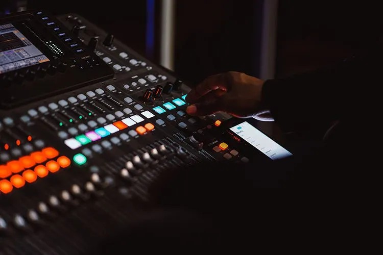 Hand adjusting controls on a digital mixing board